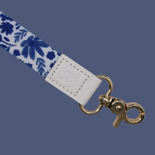 Keychain strap with blue floral pattern and gold clasp on a dark blue background